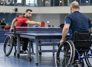 Divi para galda tenisisti riteņkrēslos izspēlē bumbiņu pie galda sporta hallē