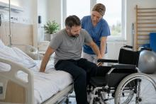 Rehabilitācijas speciāliste palīdz pacientam droši pārsēsties no slimnīcas gultas riteņkrēslā