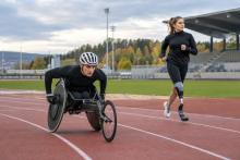 Riteņkrēsla sprinteris un sportiste ar protēzi trenējas vieglatlētikas stadionā