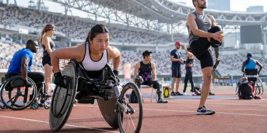 Para sportisti stadionā iesildās pirms sacensībām, tostarp sportiste sacensību riteņkrēslā