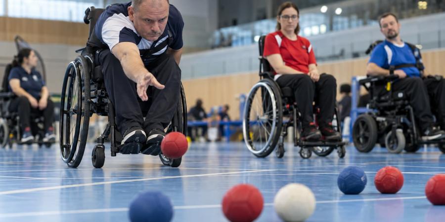 Bočas sportists met sarkanu bumbu mērķa virzienā iekštelpu sacensību laukumā