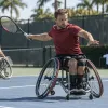 Riteņtenisists sporta riteņkrēslā izpilda sitienu āra kortā