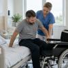 Rehabilitācijas speciāliste palīdz pacientam droši pārsēsties no slimnīcas gultas riteņkrēslā