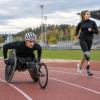 Riteņkrēsla sprinteris un sportiste ar protēzi trenējas vieglatlētikas stadionā