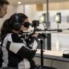Sportiste ar aizsegtām acīm un austiņām mērķē ar pneimatisko šauteni trenera klātbūtnē