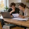 Students un viņa mamma pie virtuves galda aizpilda pabalsta pieteikumu datorā