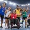 Dažādu parasporta disciplīnu sportisti stadionā kopā svin izcīnītās medaļas