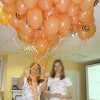 Dalībnieces ar oranžu balonu pušķi
