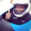 Sportists ķiverē bobslejā rāda paceltu īkšķi