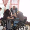 Divas sportistes ratiņkrēslos roku cīņas duelī
