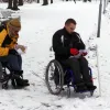 Divi dalībnieki ratiņkrēslos pēta orientēšanās kartes