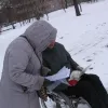 Dalībnieks ratiņkrēslā lasa orientēšanās karti