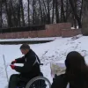Dalībnieks ratiņkrēslā salīdzina karti ar apkārtni